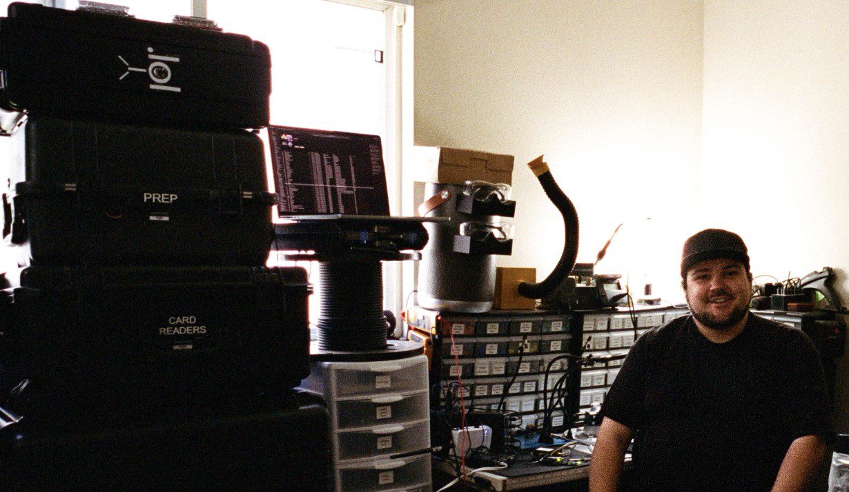 Sam Petrov sits at his workbench and smiles for a photo